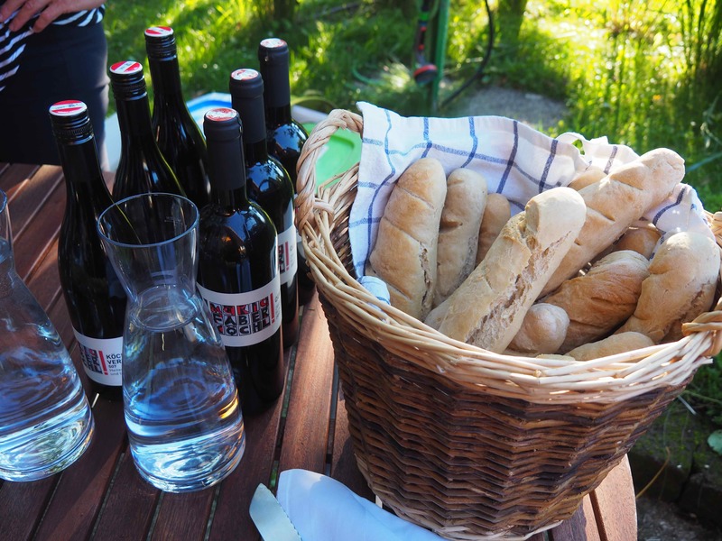 Weinflaschen und ein Korb voll frischen Baguettes auf einem Tisch